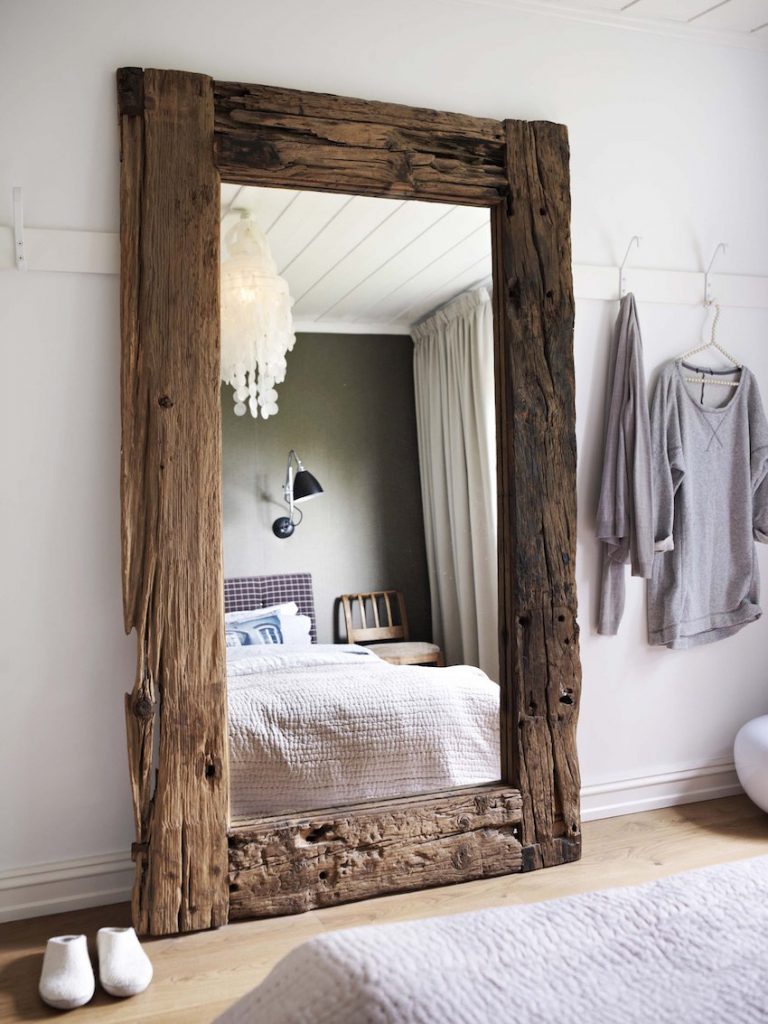 A large mirror with a wide wooden frame for the bedroom