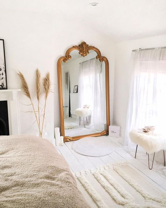 A large mirror with a gilded frame for a bright bedroom